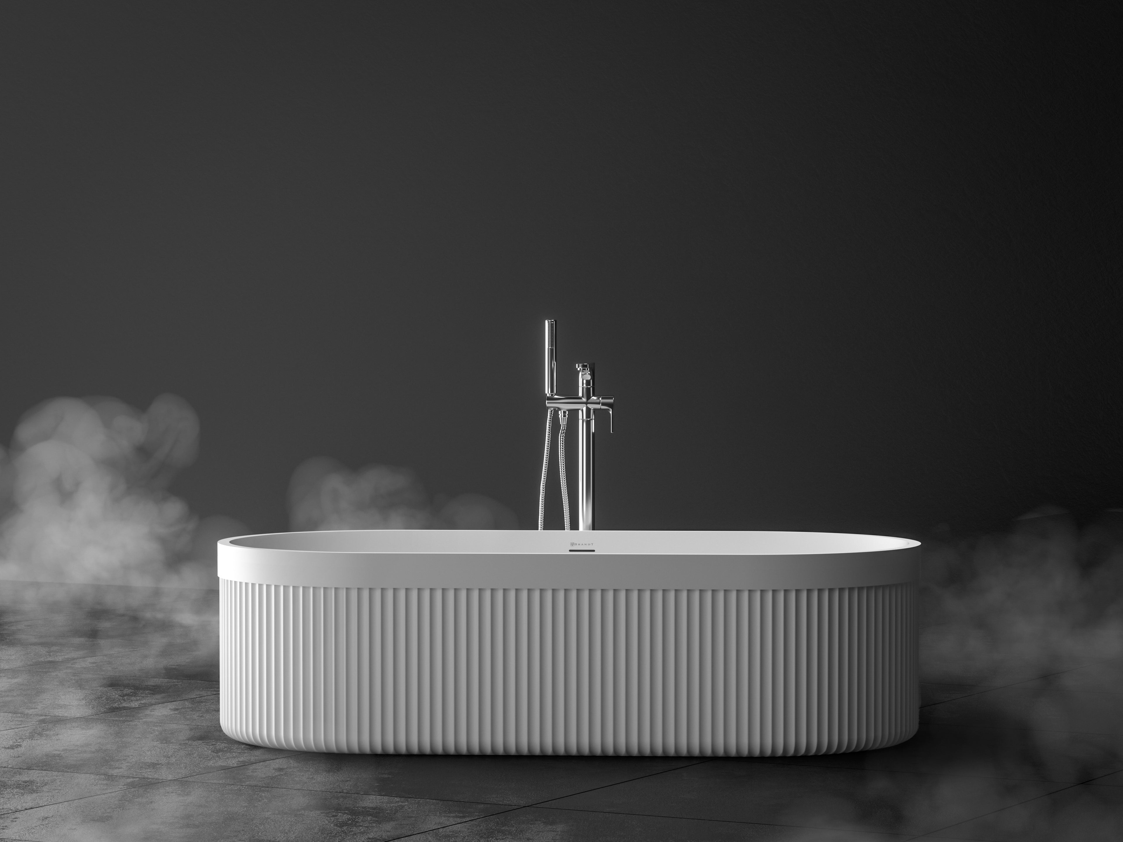 Eksklusivt 1800 mm frittstående badekar i helstøpt hvit silkematt Brandt Solid Surface med rillete sider og en glatt kant som strekker seg rundt hele badekaret. Badekaret står på et mørkt betonggulv med damp rundt.
