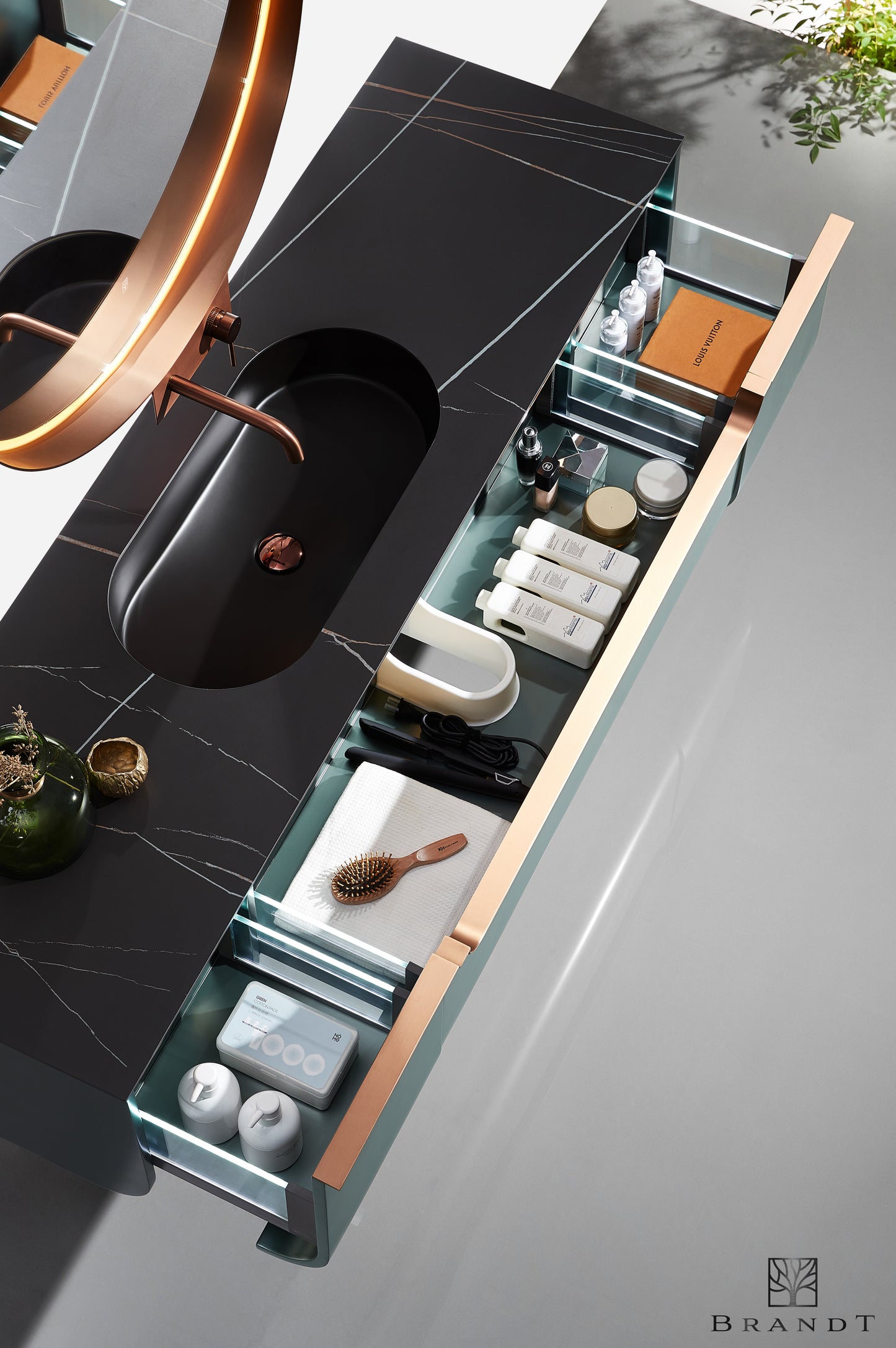 Vegghengt design baderomsmøbel i grønn metallic og detaljer i kobber sett ovenfra med åpne skuffer. Eksklusiv benkeplate i sort kompositt med marmoreringer.