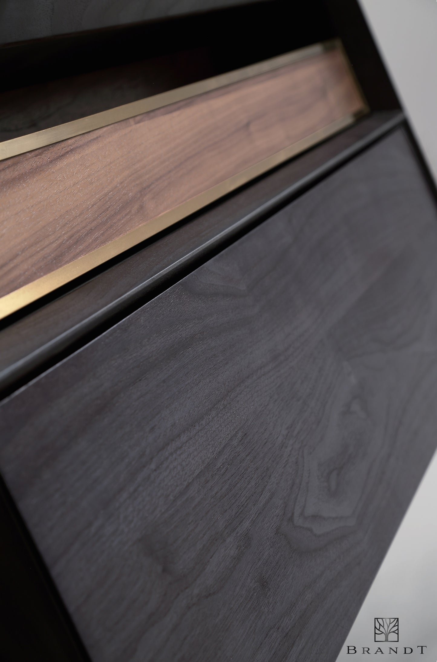 Nærbilde av front på design baderomsmøbel bygget i heltre eik med sort beis og detaljer i messing.