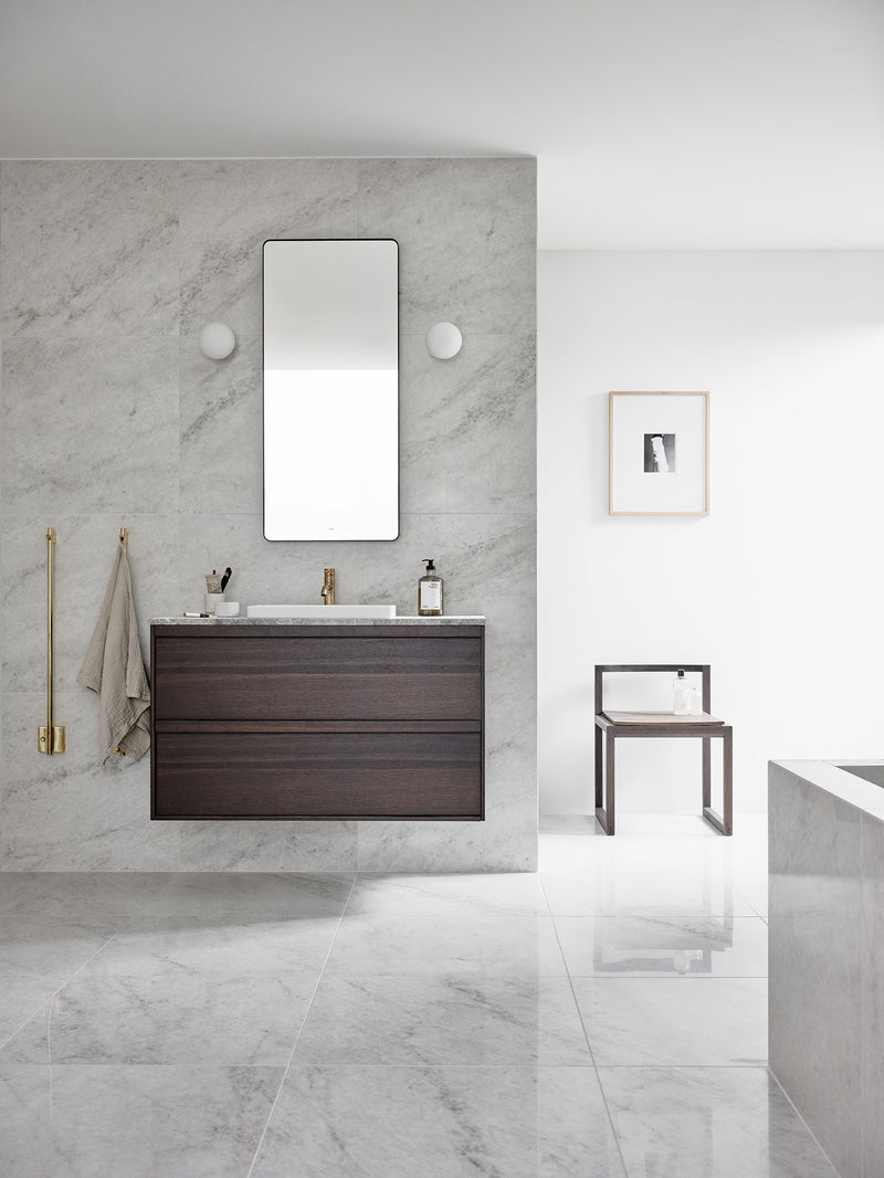 Stort lyst baderom med hvite marmorfliser og baderomsmøbel i mørkt tre med HT4328 nedsenket Servant i Matt Hvit, EVM072 Servantbatteri og TW750-85 Håndkletørkere i Oksiderende Messing.