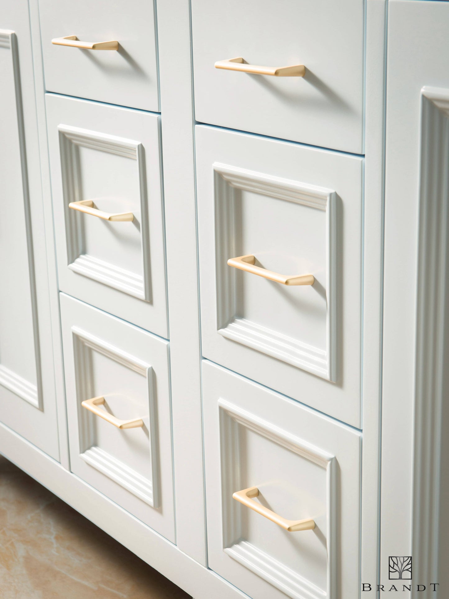 Nærbilde av skuffer på hvitt baderomsmøbel fra Brandt Bad med omramming av klassiske lister, og med håndtak av matt børstet messing.
