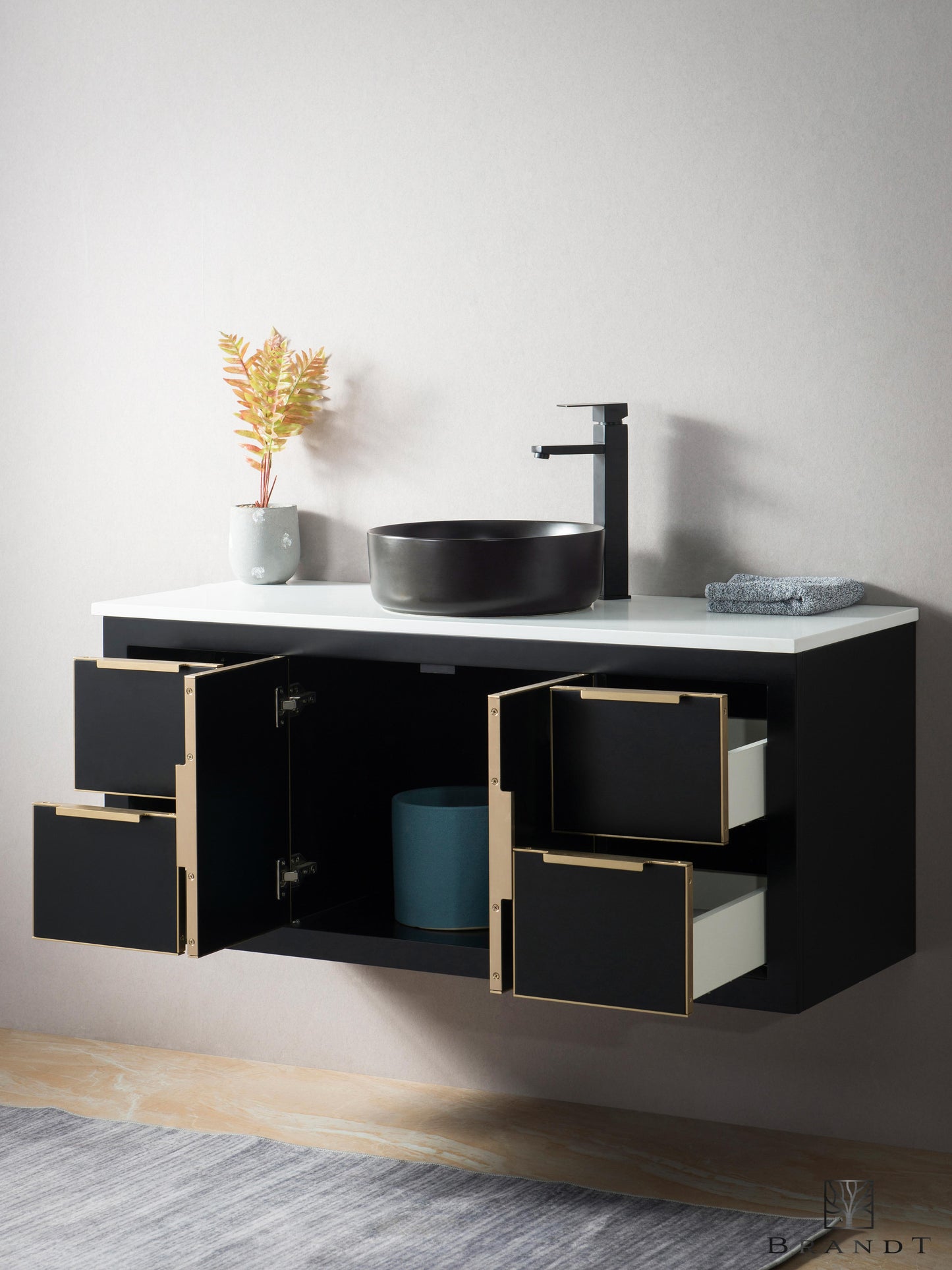 Moderne 120 cm Sort Vegghengt Baderomsmøbel fra Brandt Bad sett skrått forfra med 4 åpne skuffer og 2 åpne skapdører. Omramming, håndtak og detaljer i messing. Benkeplate i Hvit Quartz kompositt med Sort Bollevask.