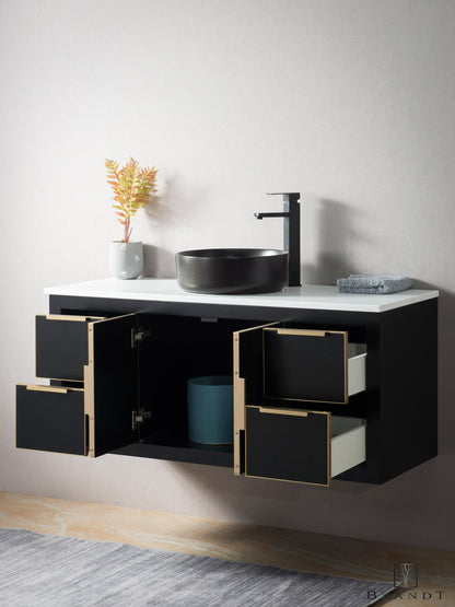 Moderne 120 cm Sort Vegghengt Baderomsmøbel fra Brandt Bad sett skrått forfra med 4 åpne skuffer og 2 åpne skapdører. Omramming, håndtak og detaljer i messing. Benkeplate i Hvit Quartz kompositt med Sort Bollevask.